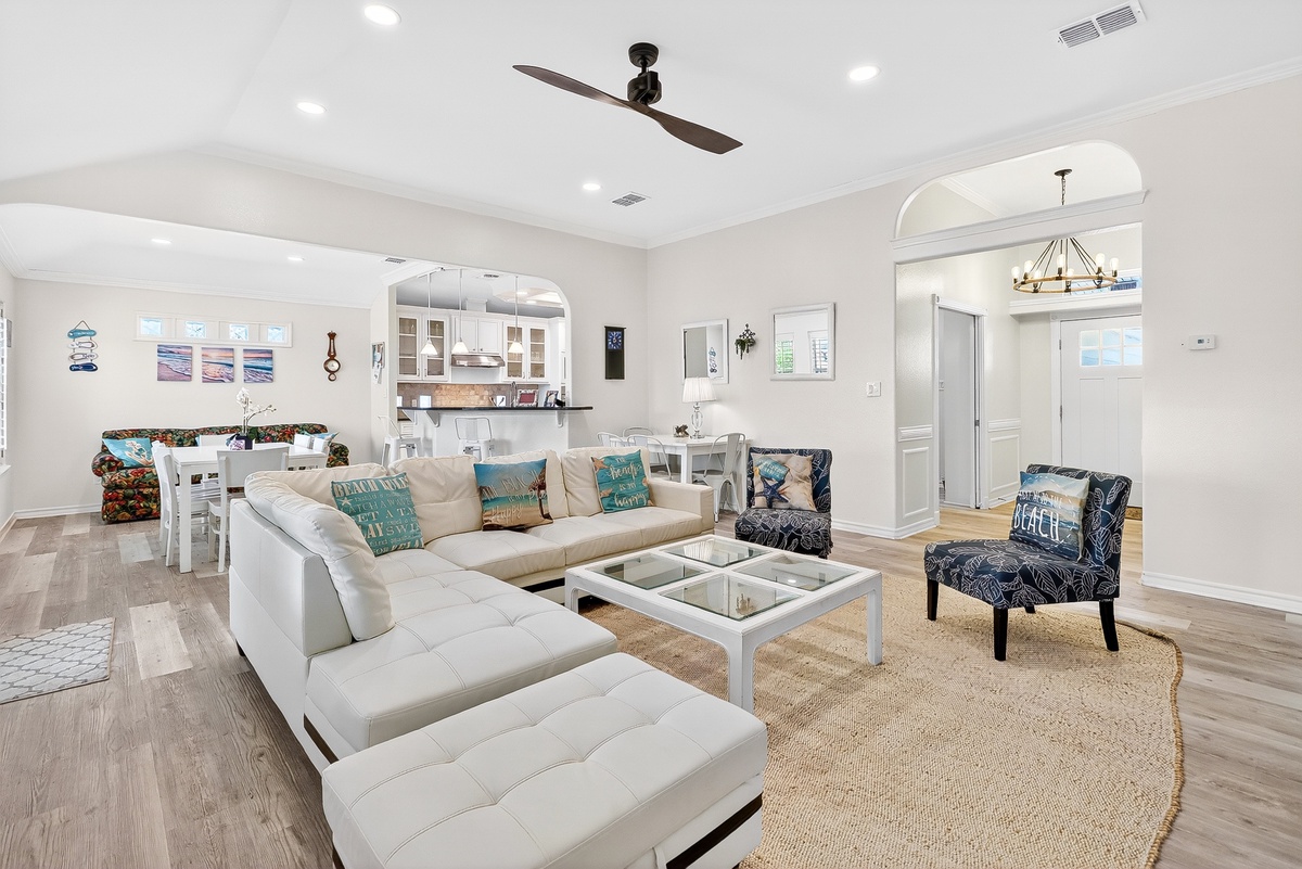 Relax in your bright, coastal-themed living space with plush seating, ocean-inspired decor, and an open layout that flows into the kitchen.