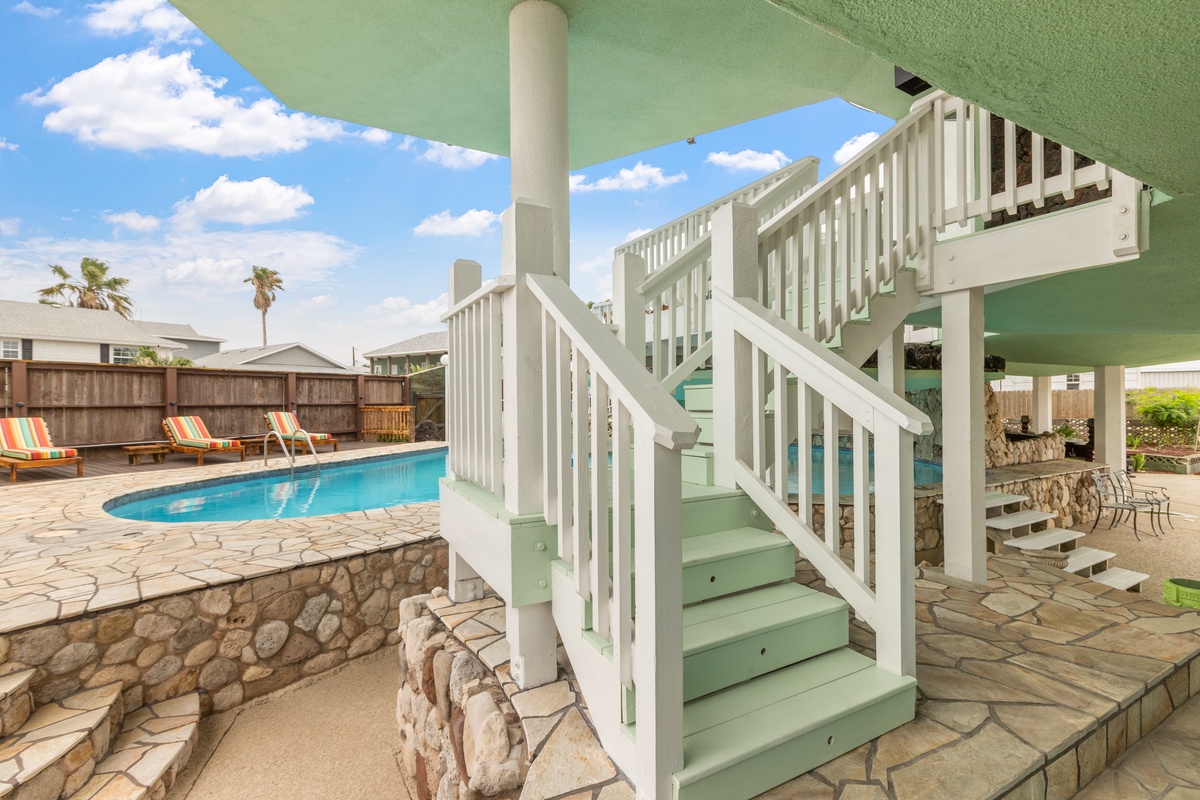 Step onto your private elevated terrace overlooking the sparkling pool, where colorful loungers await your sun-soaked afternoons in this tropical paradise.