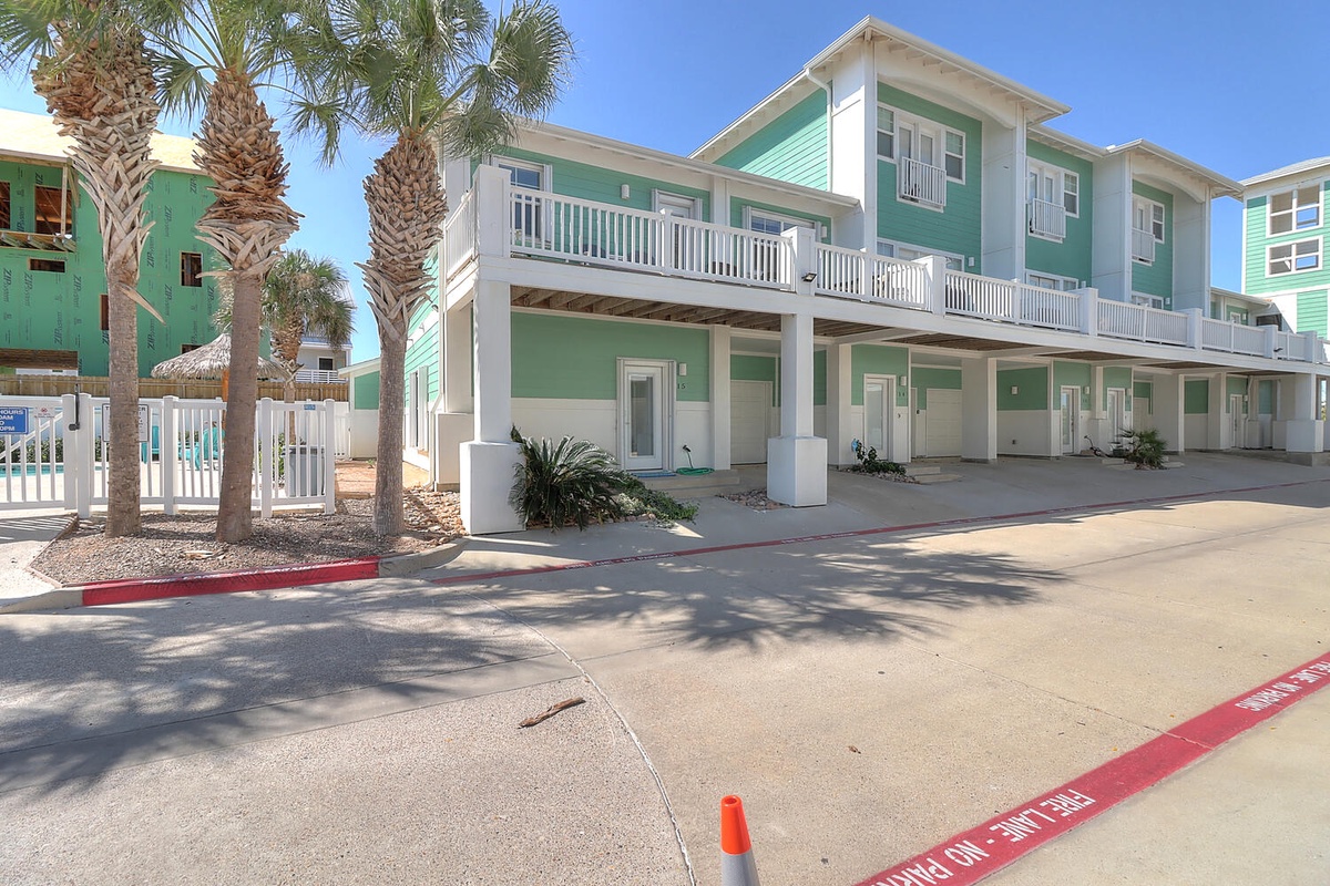 Coastal-themed property featuring bright green siding and palm-lined entrance in a tropical beach setting.