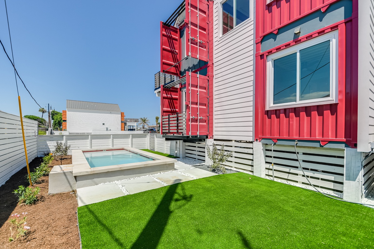 Modern building complex with a private pool and landscaped yard area in a residential neighborhood setting.
