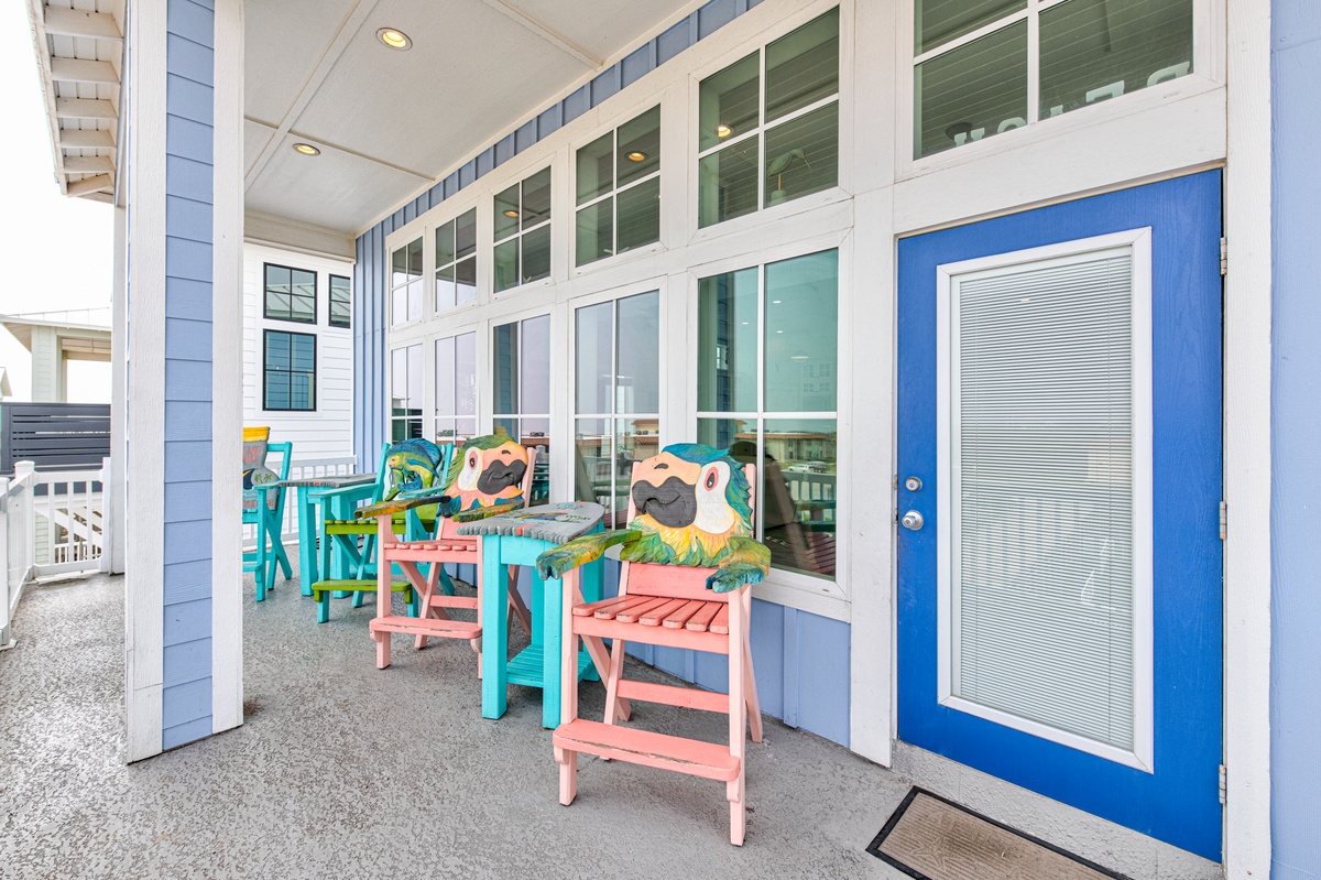 Relax on your covered porch with colorful beach furniture and whimsical lighthouse decor, perfect for morning coffee or evening unwind.