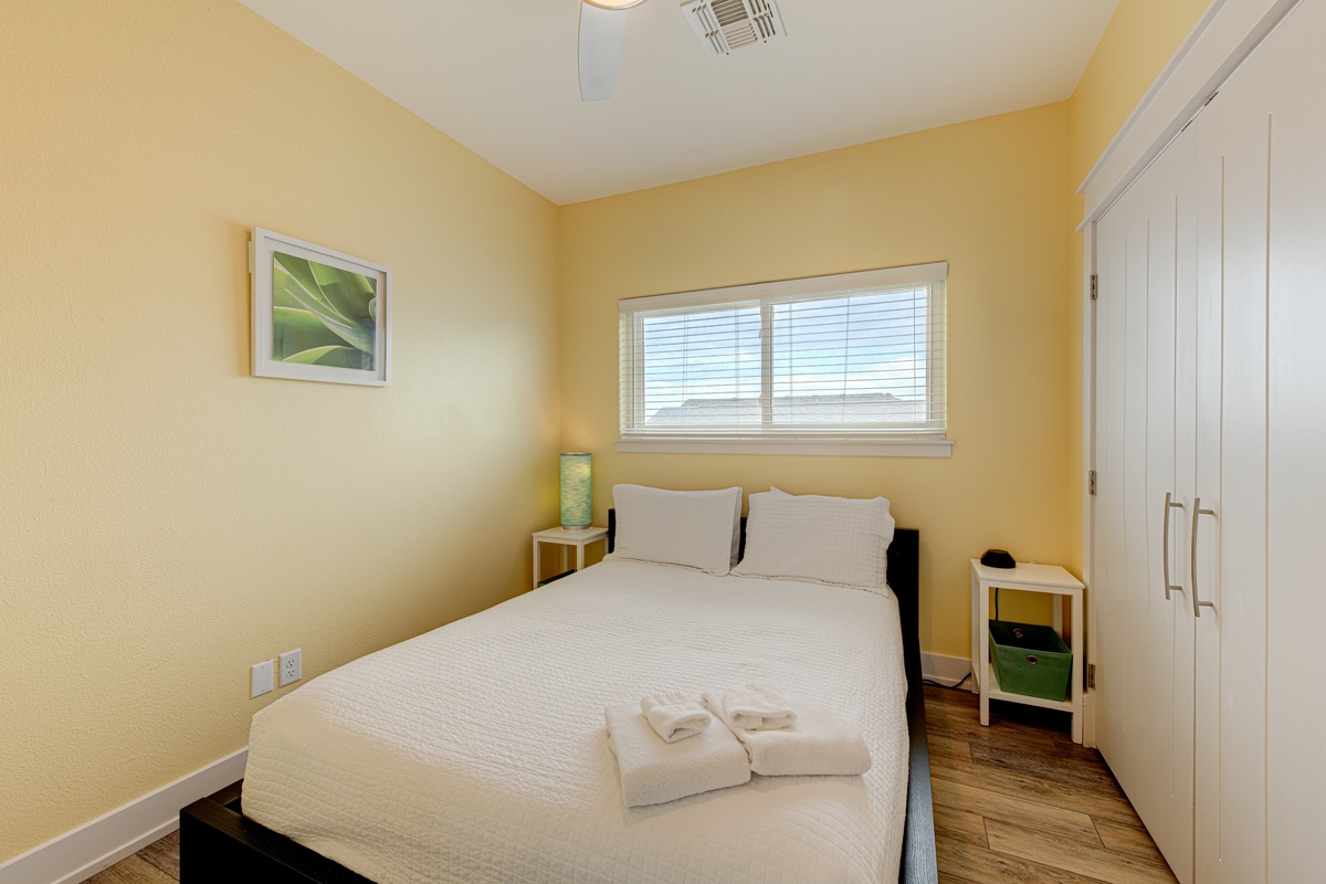 Your sunny bedroom awaits with crisp linens, warm yellow walls, and thoughtful touches like fresh towels ready for your arrival.