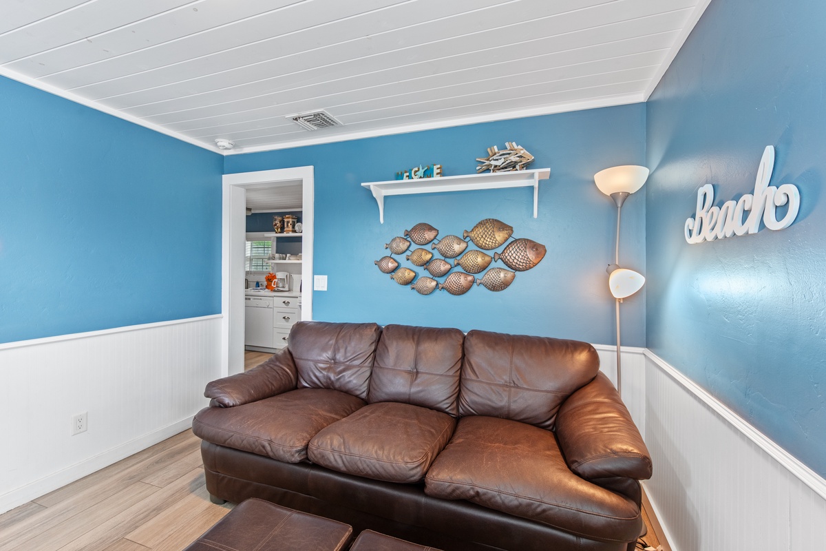 Sink into the plush leather sofa and let the ocean-themed decor transport you to coastal bliss in your beach-inspired retreat.