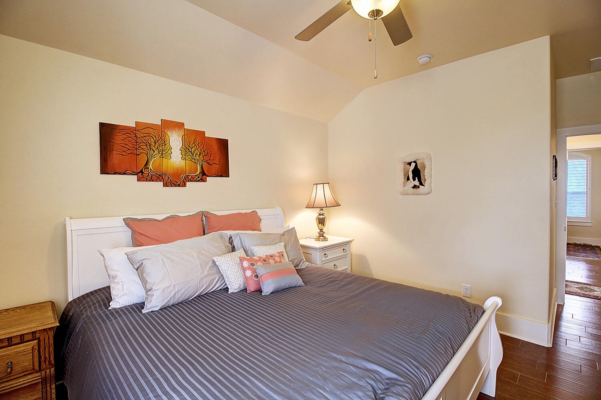 Sink into crisp linens and colorful pillows in your peaceful bedroom retreat, complete with warm artwork and gentle ceiling fan.