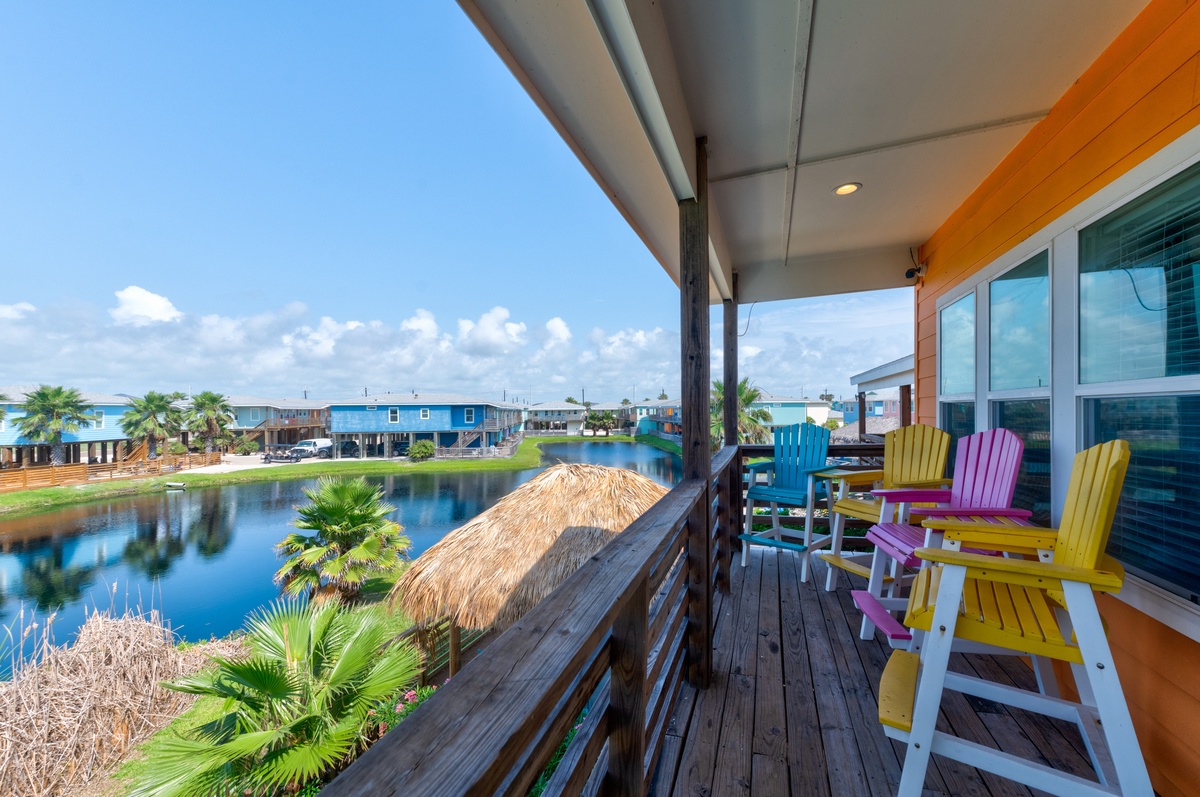 Relax on your private deck with colorful Adirondack chairs overlooking the tranquil canal, where tropical palms frame peaceful water views.