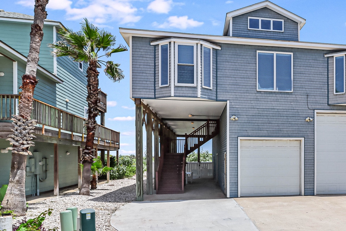 Charming coastal home with covered parking and tropical palms in a beachside neighborhood setting.