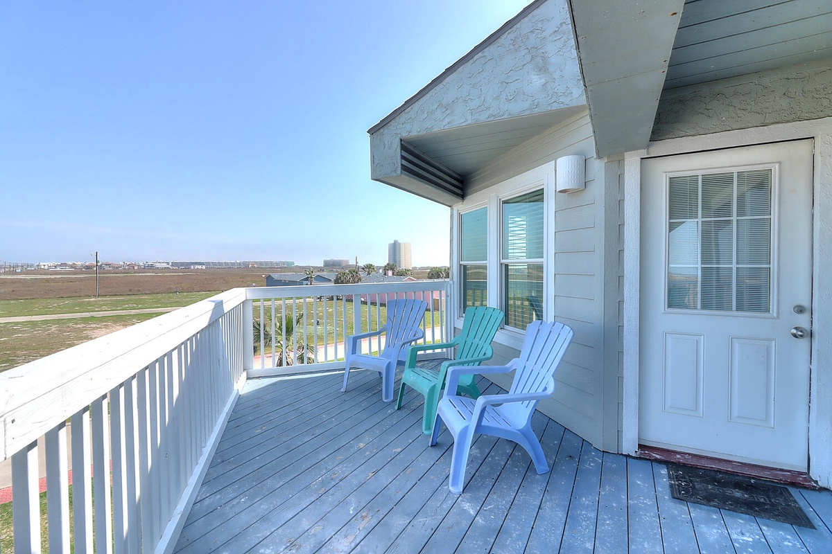 Relax on your private deck with colorful Adirondack chairs while soaking in sweeping views of the coastline and distant cityscape.