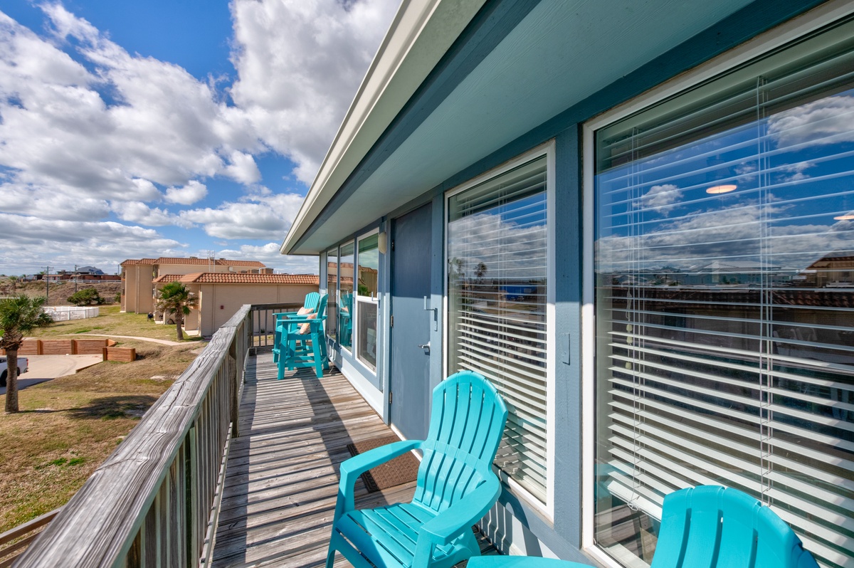 Unwind on your private balcony with turquoise chairs overlooking the peaceful neighborhood below.