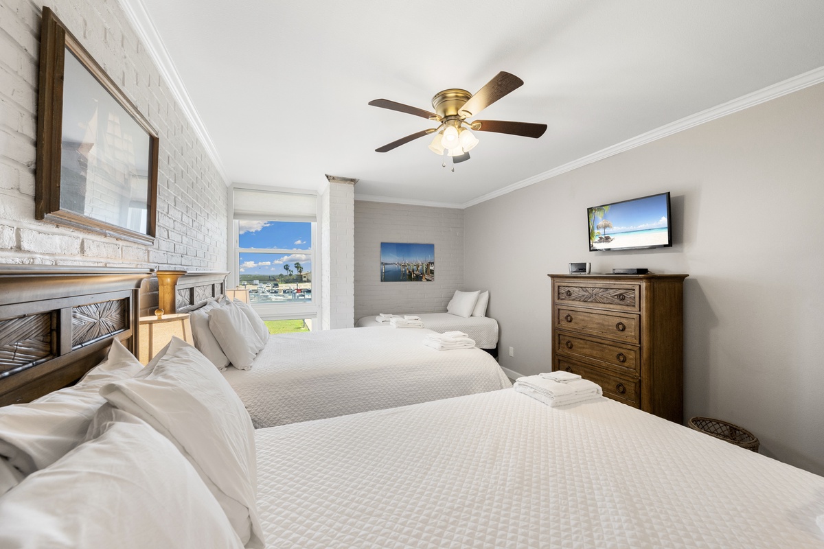 Rest peacefully in this coastal bedroom with twin beds, crisp linens, and gentle ceiling fan circulation.