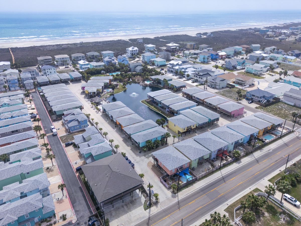 Aerial view of beachfront community with colorful vacation homes nestled between the ocean and residential neighborhoods.