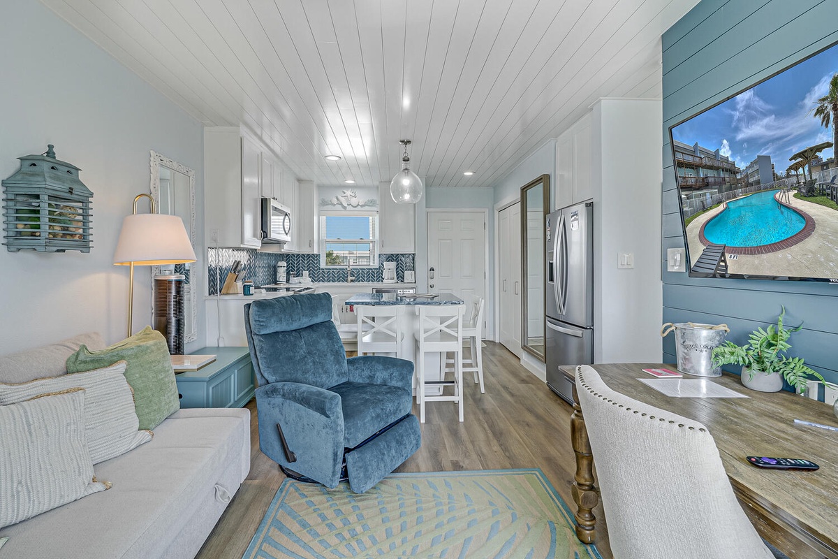 Step into your coastal-inspired open living space where blue tones and white beadboard create a serene atmosphere for relaxing after beach adventures.