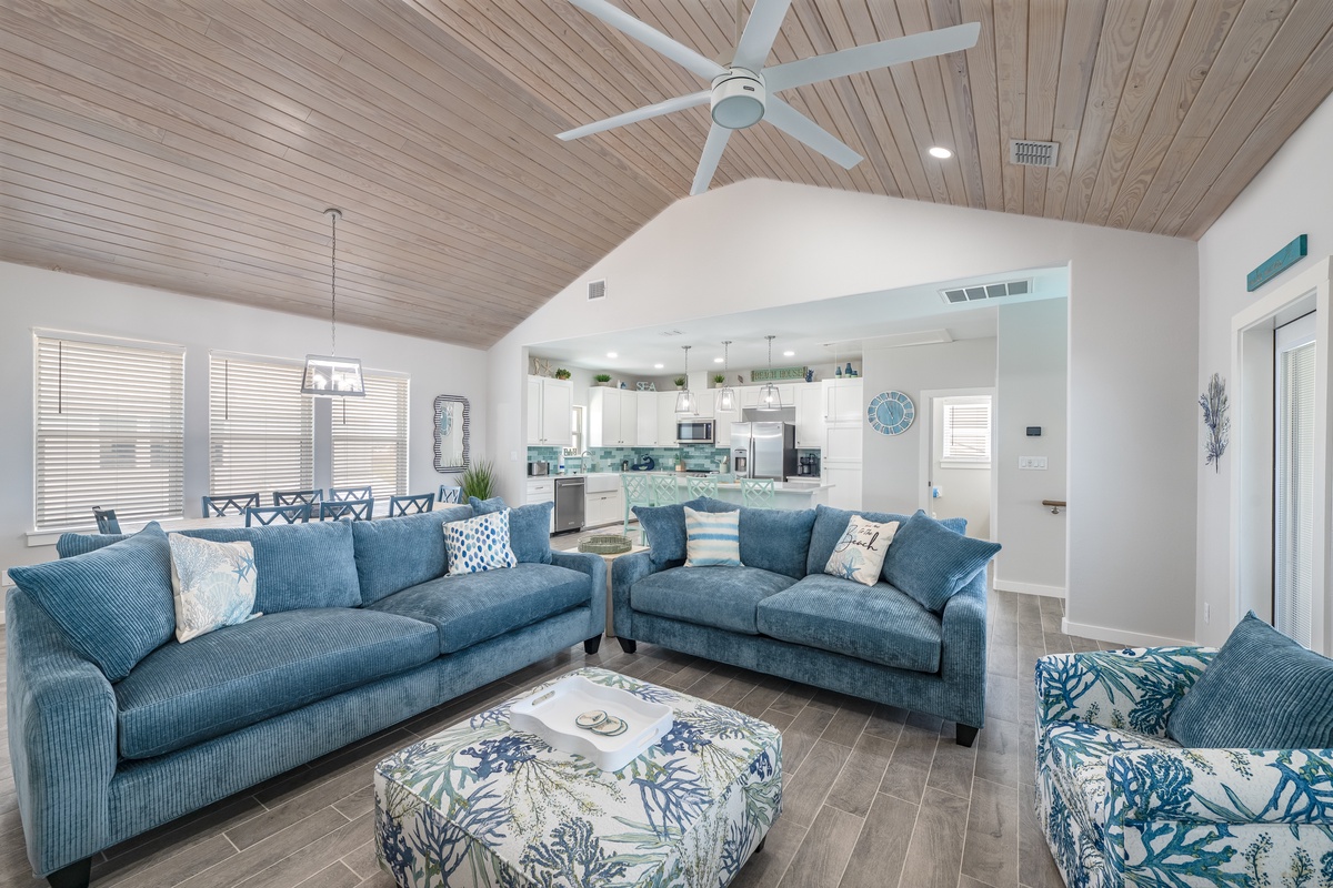 Sink into plush coastal sofas and feel the ocean breeze from your ceiling fan in this stunning open-concept retreat.
