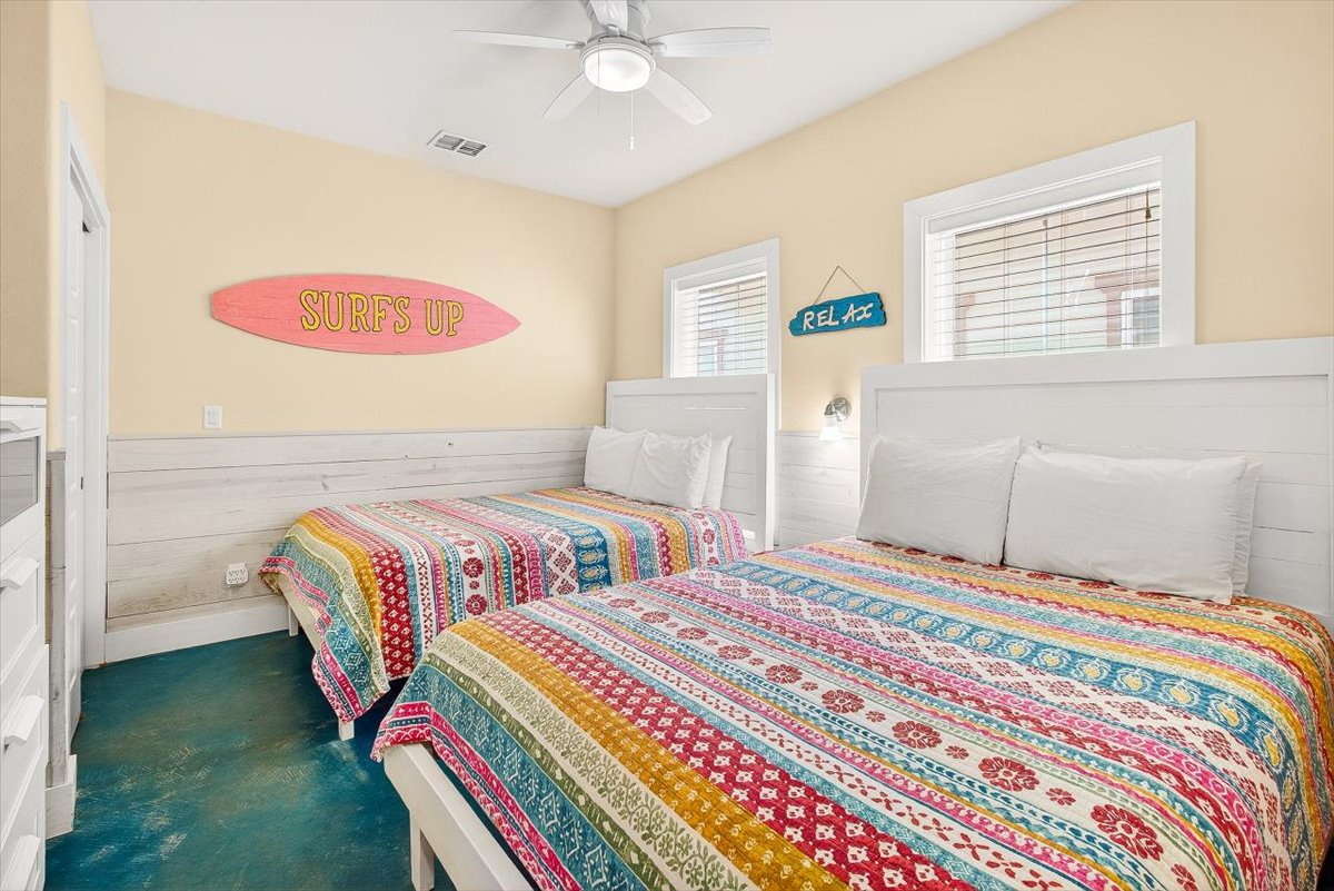 Unwind in your vibrant twin bedroom featuring colorful bohemian quilts, beach-themed décor, and natural light streaming through windows.