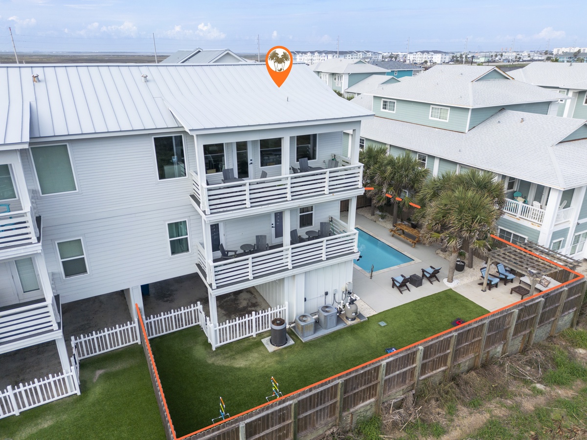 Aerial view of beachside vacation rental with swimming pool, outdoor seating areas, and coastal neighborhood setting.