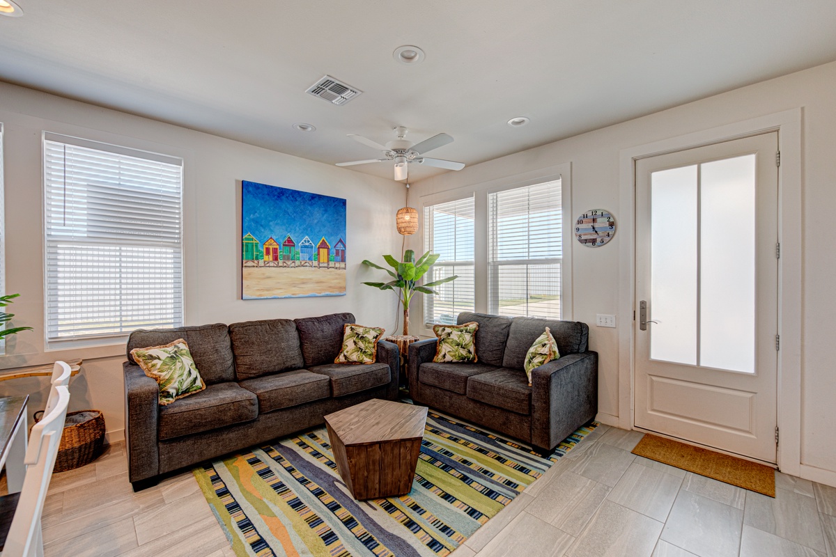 Unwind in your bright, coastal-themed living room with comfortable sectional seating and cheerful beach house artwork to set your vacation mood.