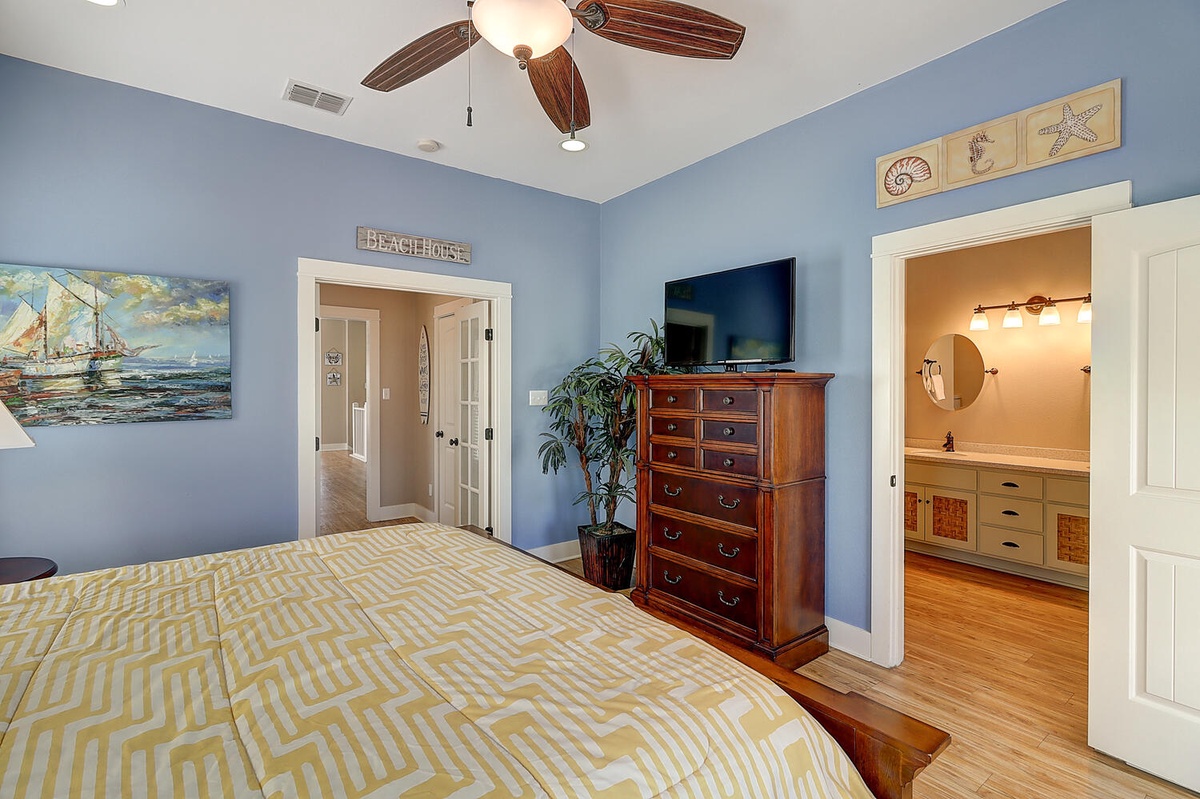 Drift off in your coastal bedroom with ocean-themed decor, ceiling fan, and private en-suite bathroom awaiting your arrival.