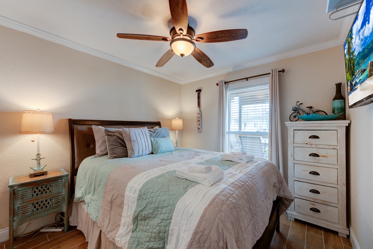 Sink into soft linens and coastal charm in your peaceful bedroom retreat, where gentle ceiling fans keep you cool.