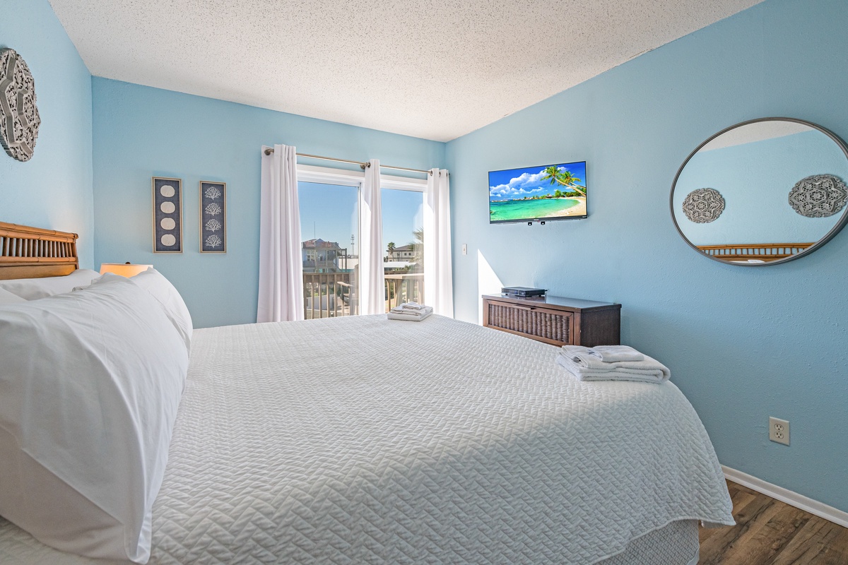 Drift off in your serene coastal bedroom with soft blue walls, tropical touches, and comfortable furnishings that welcome peaceful sleep.