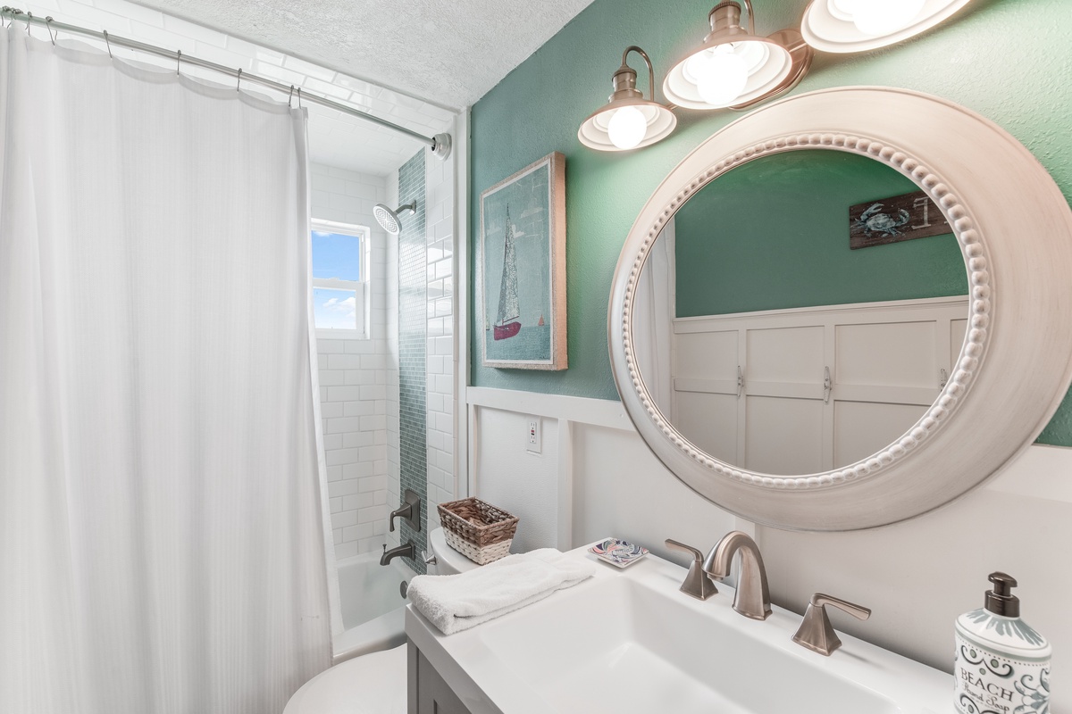 Refresh in your coastal-themed bathroom with subway tile shower, round mirror, and charming nautical touches that make every morning feel like a seaside escape.