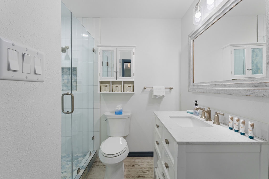 You'll love this pristine bathroom with its spacious glass shower, marble vanity, and thoughtful amenities ready for your stay.