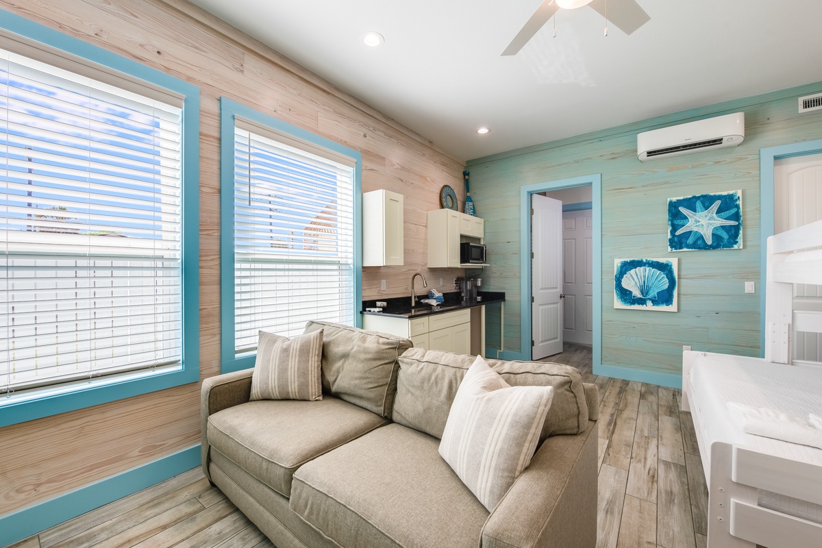 Relax in your bright beach cottage with coastal charm, featuring a cozy sofa, full kitchenette, and soothing turquoise accents throughout.