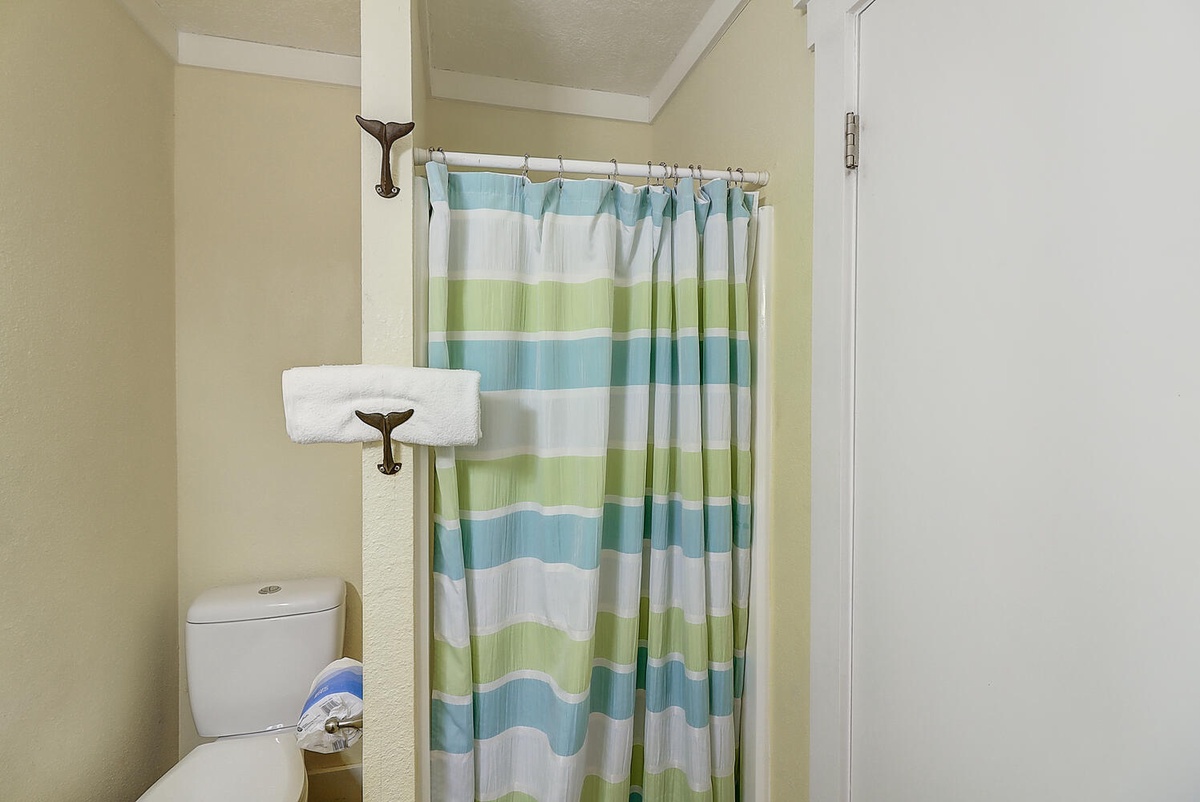 Step into your private bathroom featuring a refreshing shower with cheerful striped curtain and fresh towels ready for your stay.
