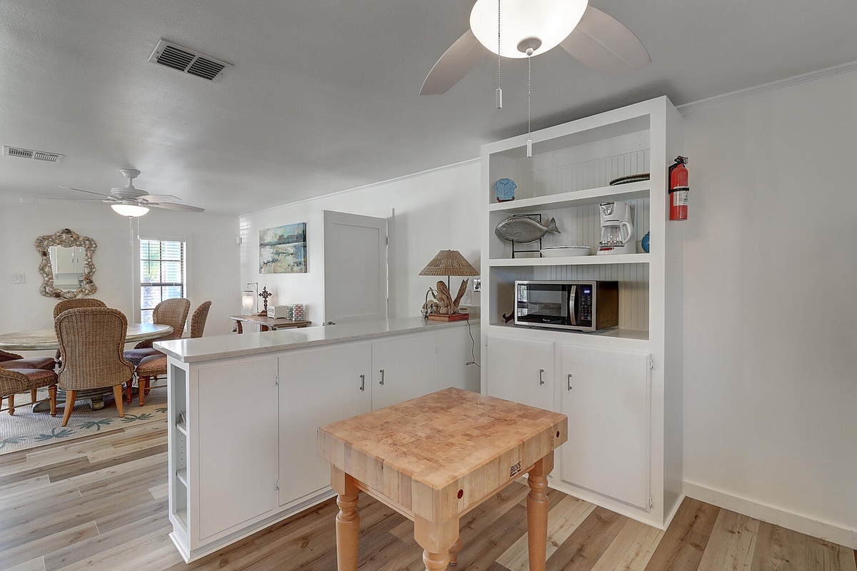 Your open kitchen flows seamlessly into the dining area, featuring a butcher block island perfect for meal prep and coastal-themed built-ins.