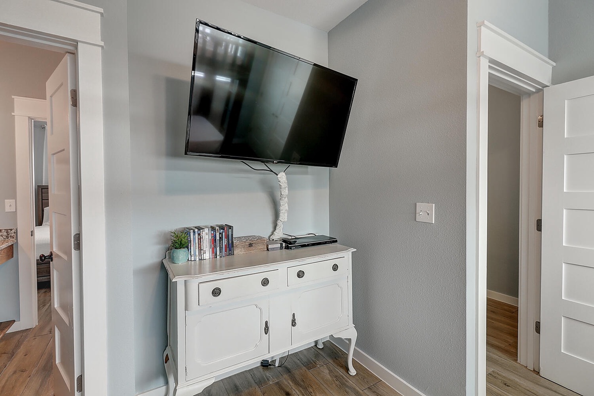 Your entertainment center awaits with a wall-mounted TV and charming vintage buffet for storing your belongings in this welcoming space.