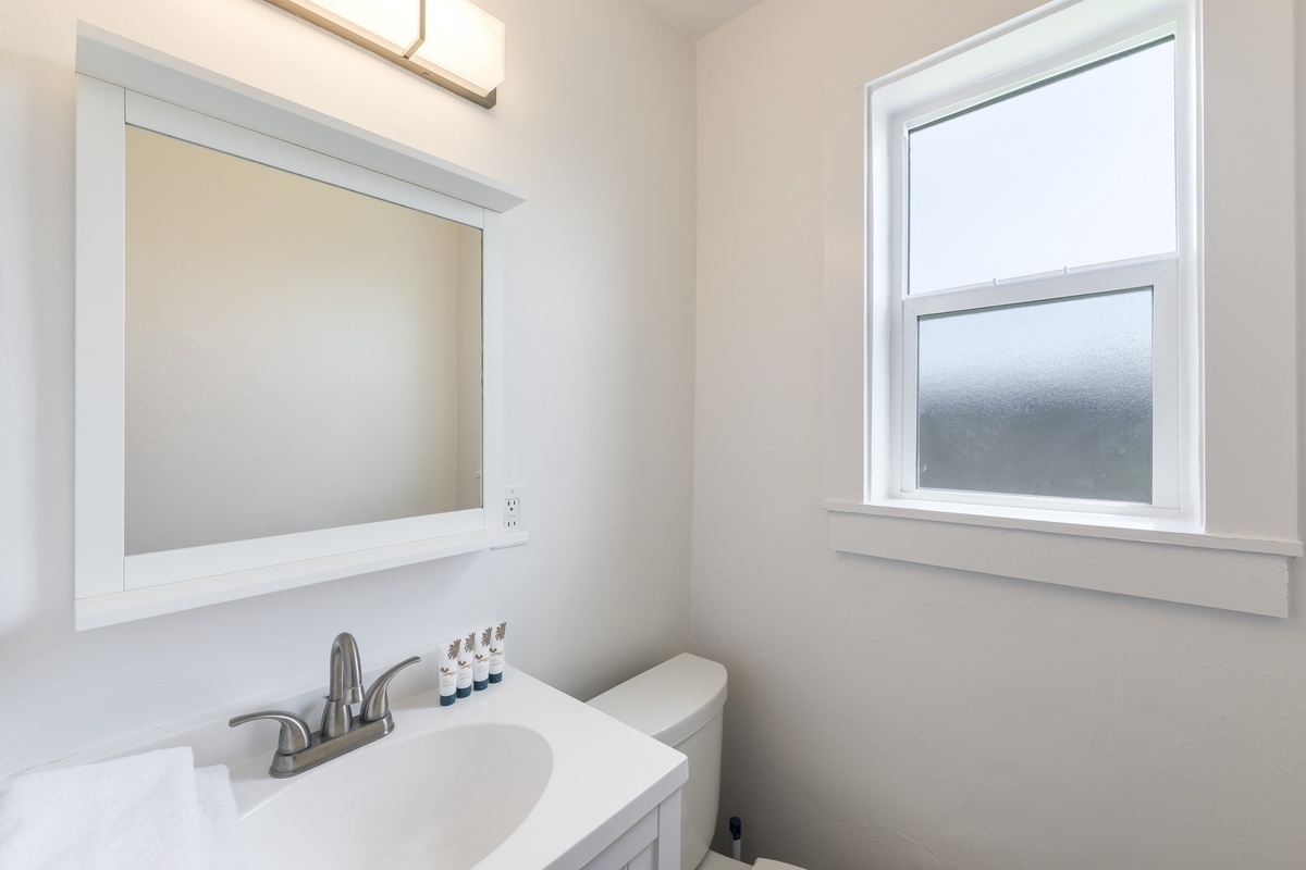 Step into your bright, thoughtfully designed bathroom where natural light streams through the window, creating a fresh and airy atmosphere. The clean lines and modern fixtures offer comfort and convenience for your stay.