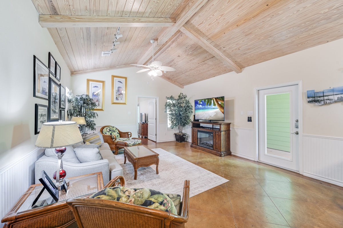 Relax in your spacious living room with vaulted wood ceilings, cozy fireplace, and tropical-themed décor that creates the perfect island retreat atmosphere.