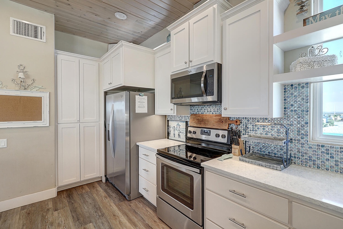 Your fully equipped kitchen features stainless steel appliances and charming coastal tile backsplash, perfect for preparing memorable meals during your stay.