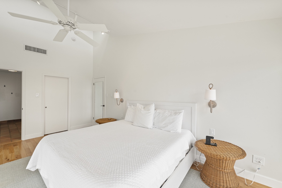 Drift off in your serene white bedroom with crisp linens and gentle ceiling fan keeping you cool all night.