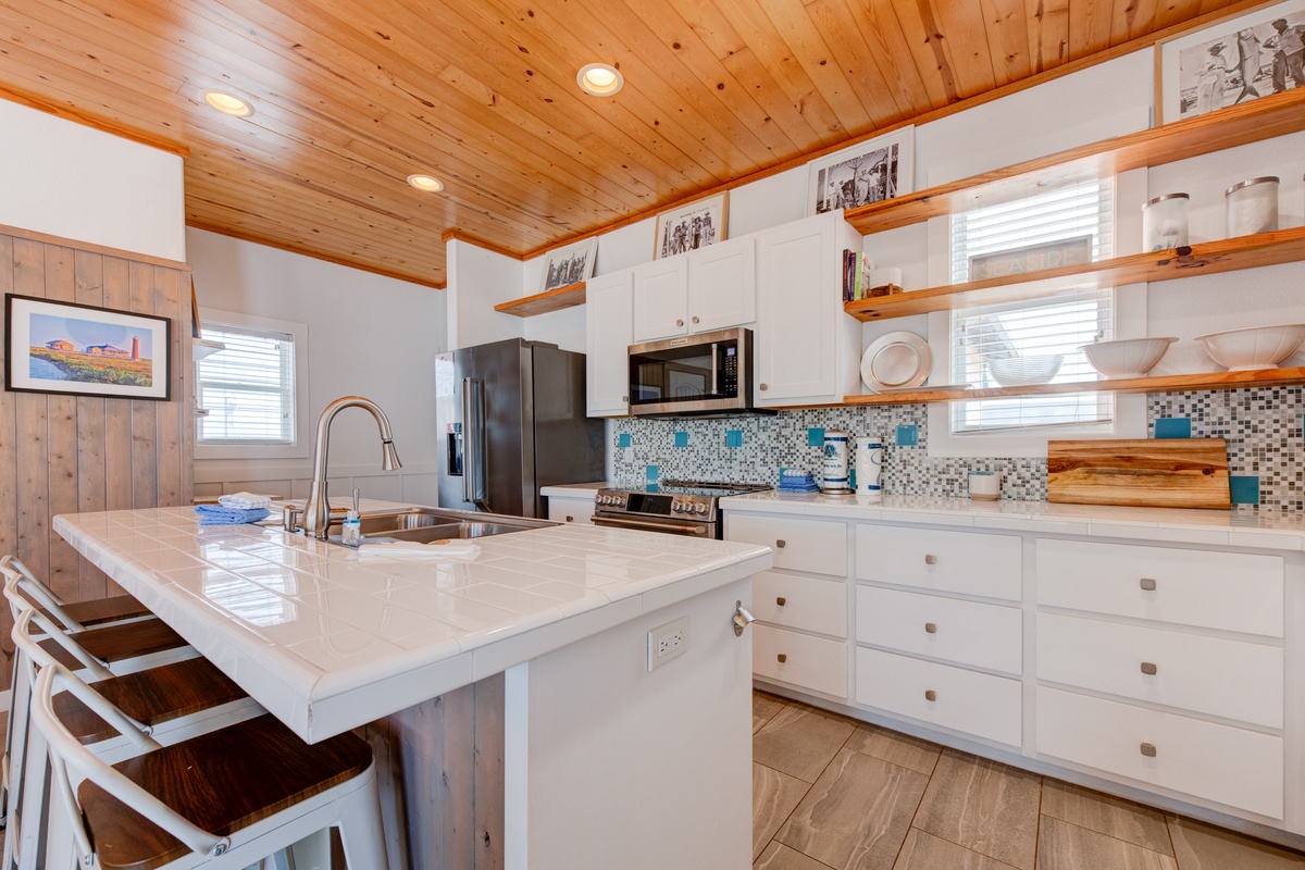 Whip up your favorite meals in this bright, fully-equipped kitchen with sleek white counters and warm wood ceiling.