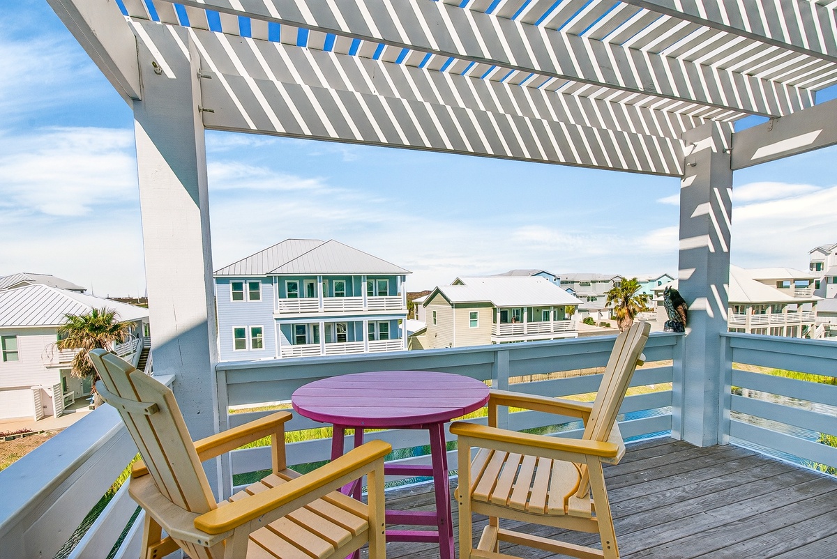 Soak up coastal charm from your private deck, where beach house views and colorful table invite lazy afternoons.
