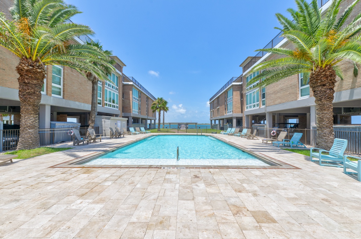 A stunning beachfront pool complex with swaying palms and modern vacation townhomes creates the perfect tropical getaway setting.