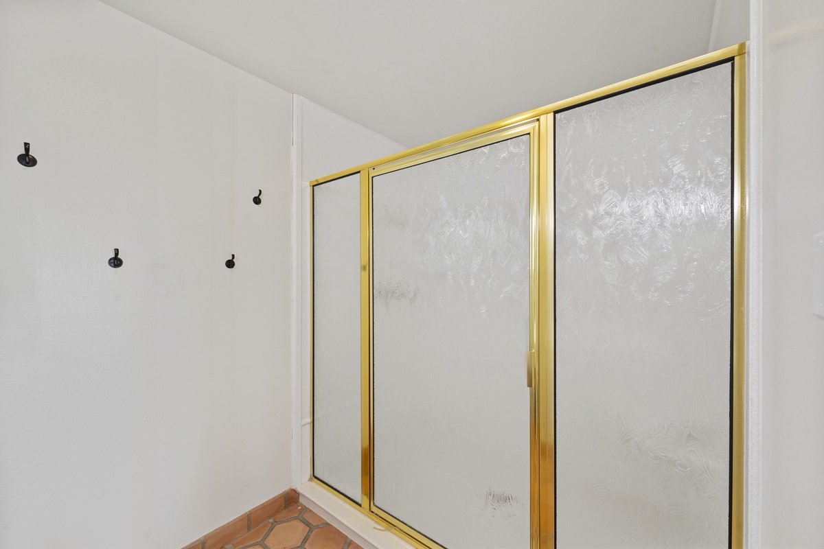 Your private shower features elegant gold-framed glass doors and multiple rainfall showerheads for a luxurious bathing experience.