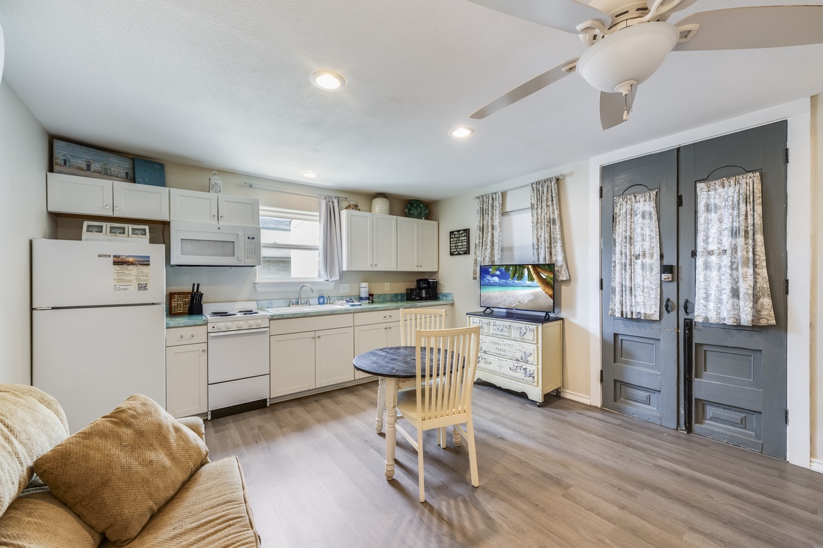 Step into your cozy coastal retreat where the open kitchen invites you to whip up beachside meals, while the breezy ceiling fan and charming seating area make every moment feel like home.