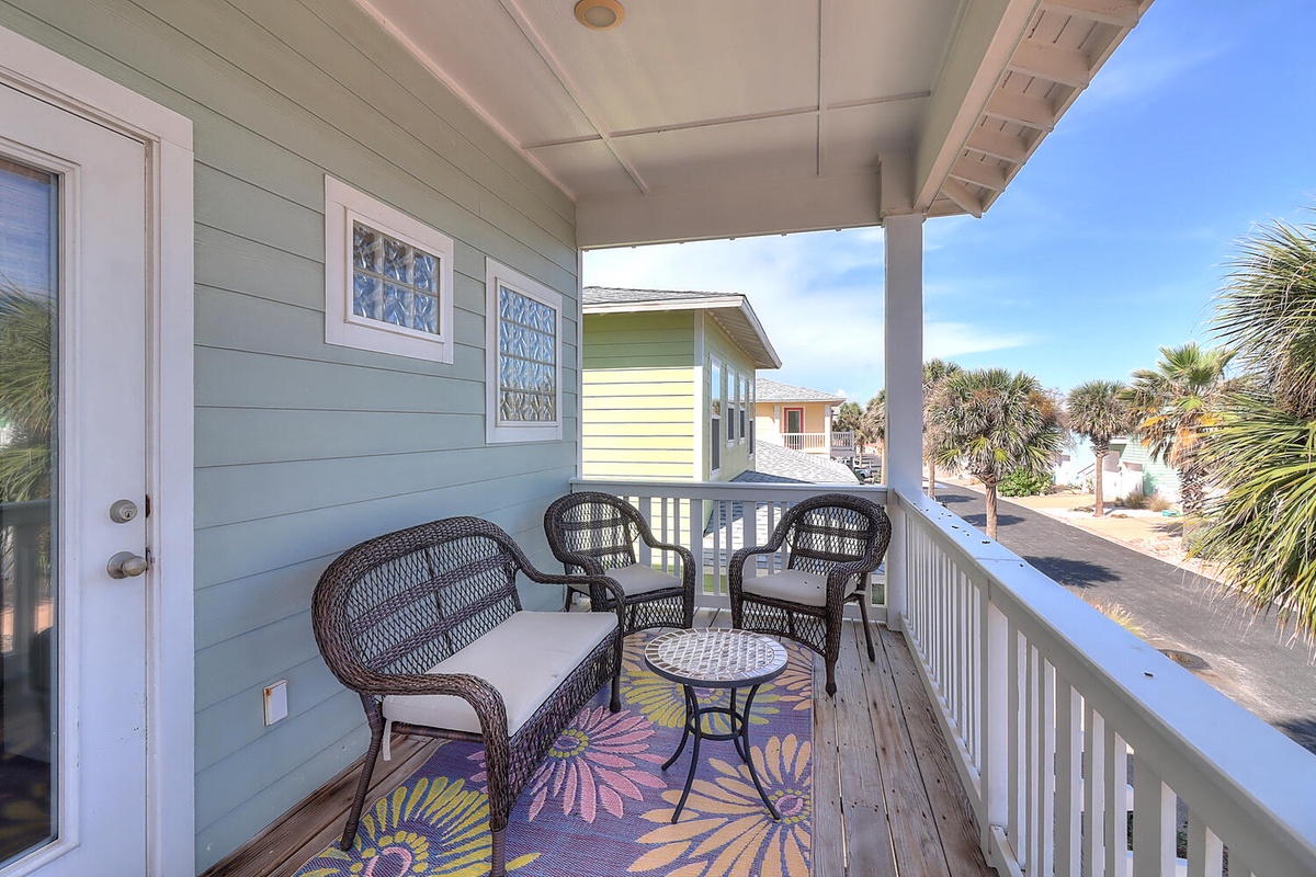 Step onto your private covered balcony and settle into cozy wicker seating with vibrant tropical decor—your perfect spot to unwind.
