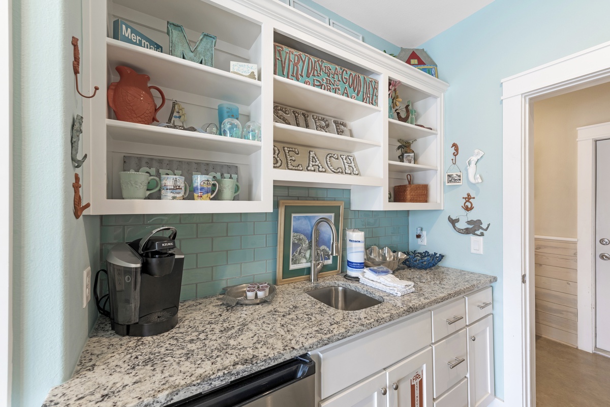 Your charming kitchenette features coastal-themed shelving with beach decor, granite counters, and everything needed for morning coffee or light meals.
