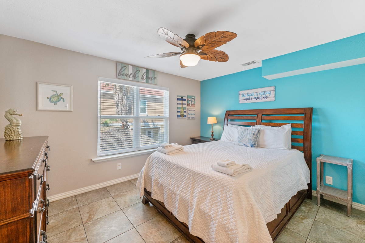 Your coastal bedroom retreat features a vibrant turquoise accent wall and tropical ceiling fan to keep you cool and comfortable.