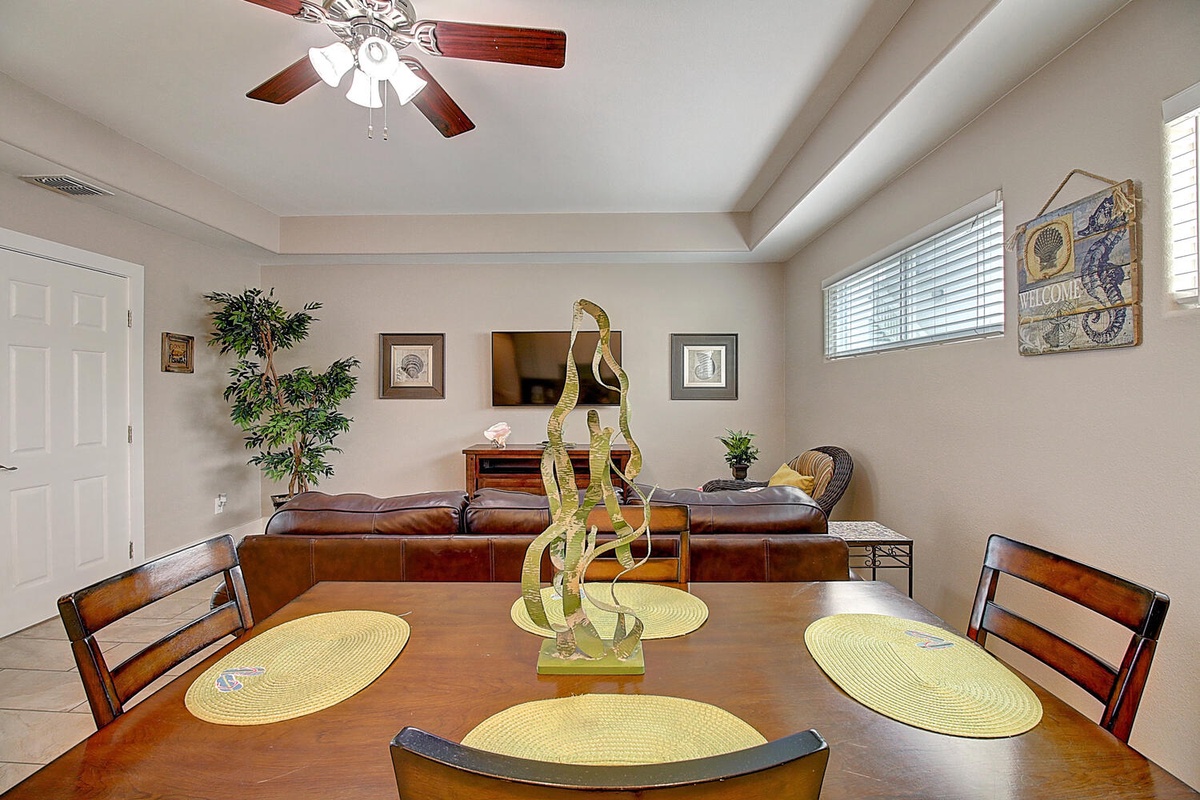 Gather around your warm dining table where thoughtful details like woven placemats and unique art create the perfect setting for memorable meals together.