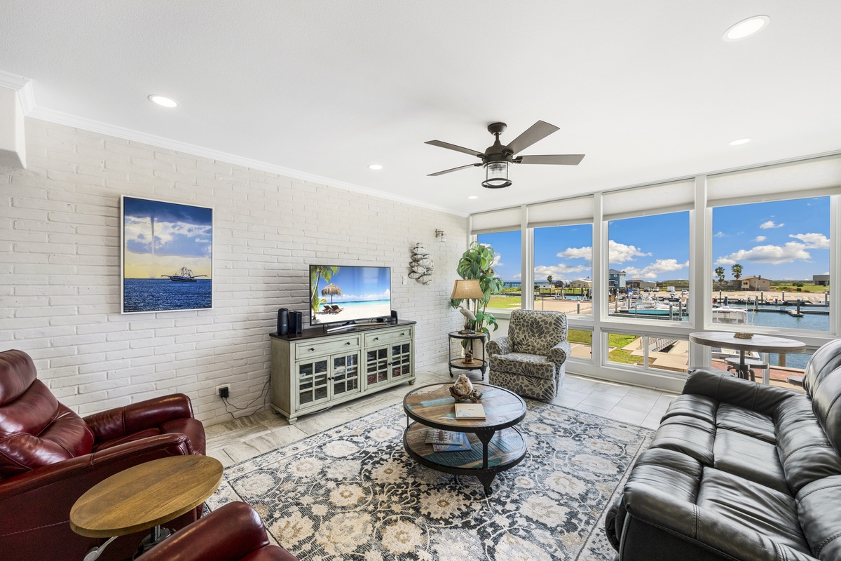 Relax in your bright living room with panoramic marina views, featuring comfortable leather seating and coastal charm.