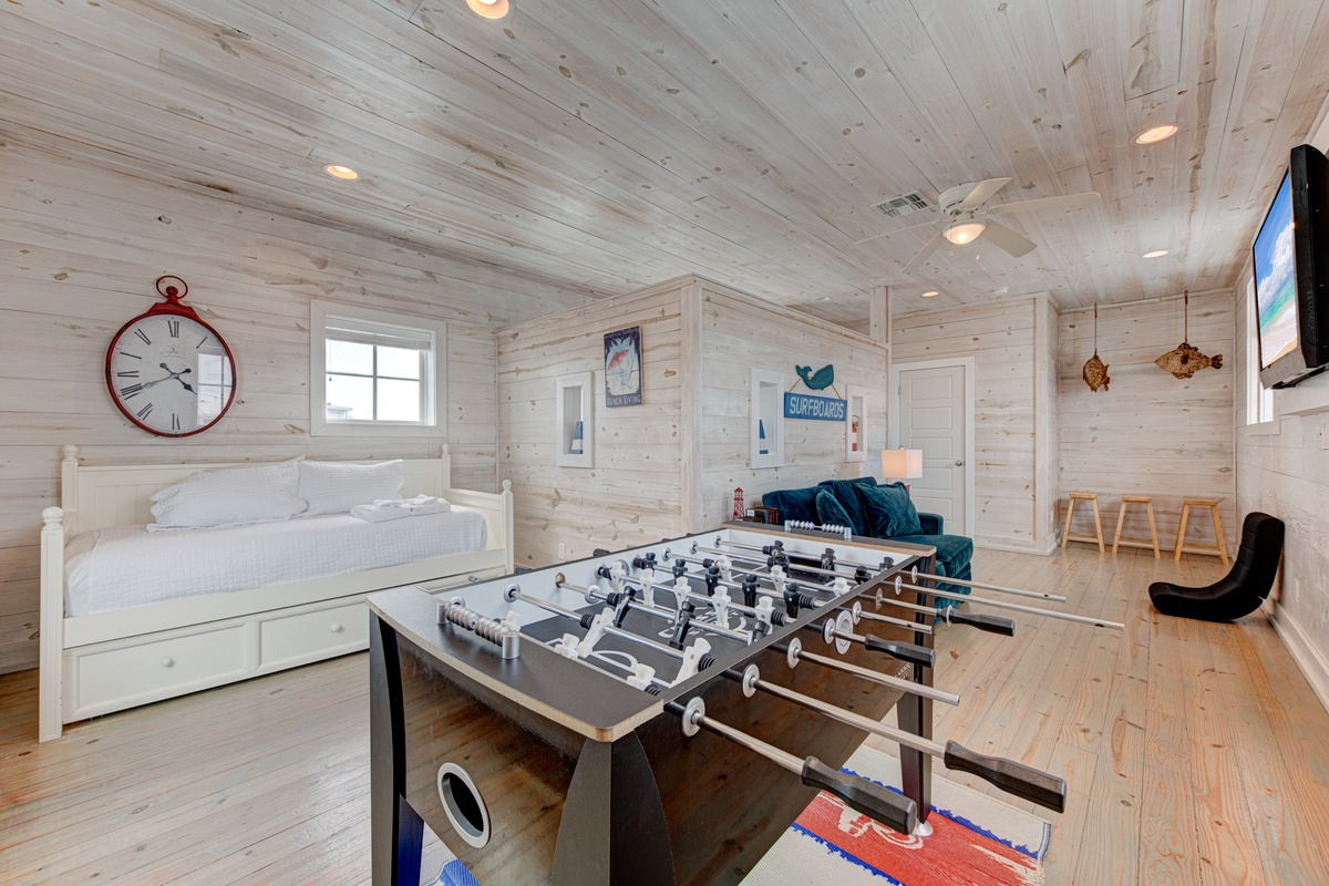 Challenge friends to foosball in your spacious game room, featuring rustic wood walls, cozy seating, and entertainment for endless fun.
