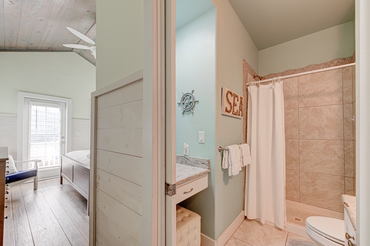Your bright bathroom features a spacious tiled shower with fresh towels and coastal charm.