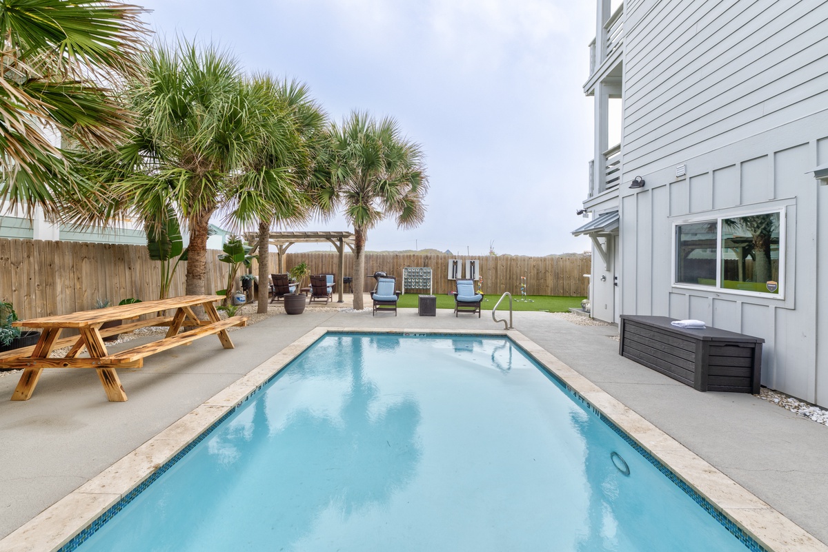 Step into your private backyard oasis with a sparkling pool, picnic table, and tropical palms for perfect poolside relaxation.
