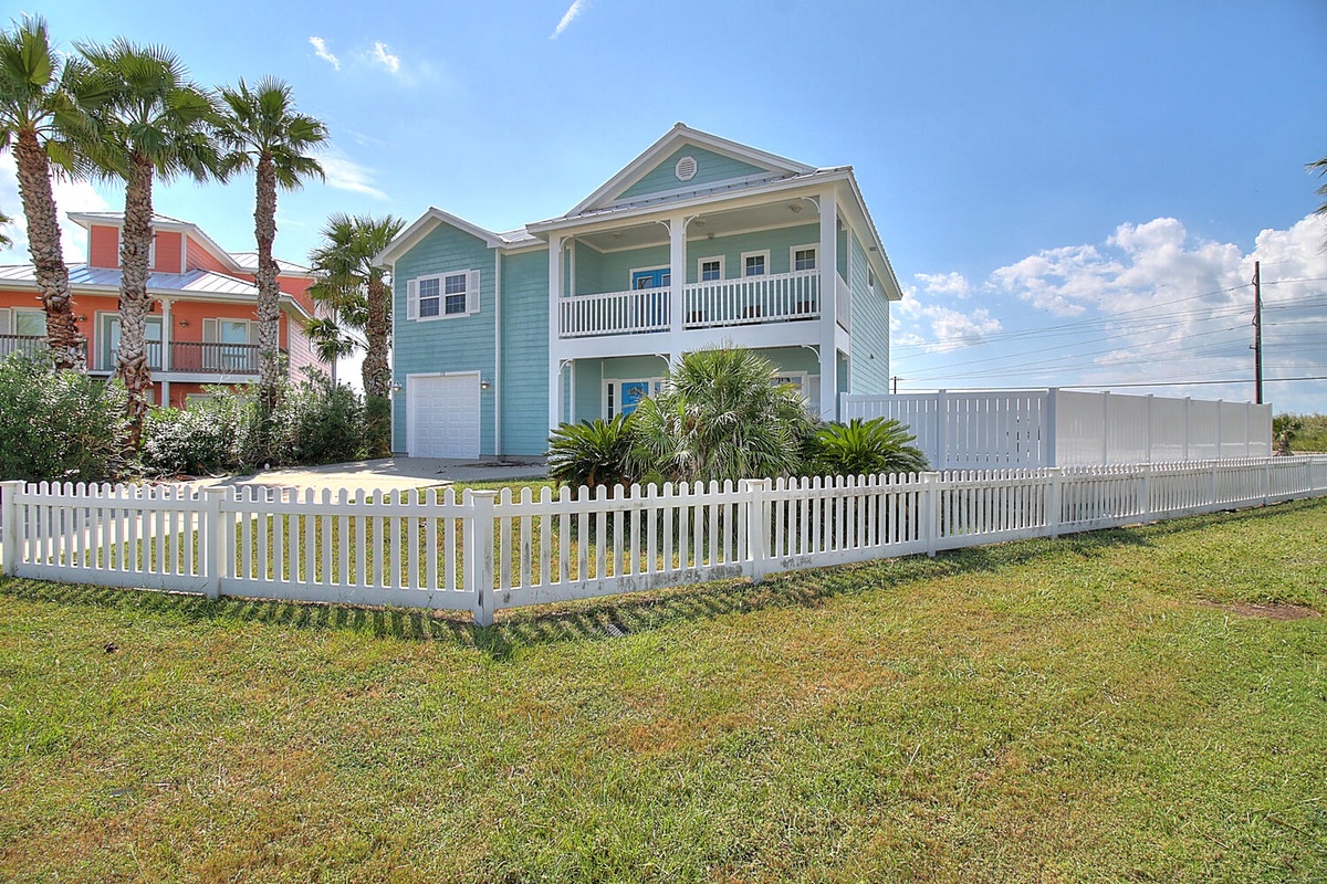 Coastal vacation home with tropical landscaping and private fenced yard in a peaceful residential neighborhood.
