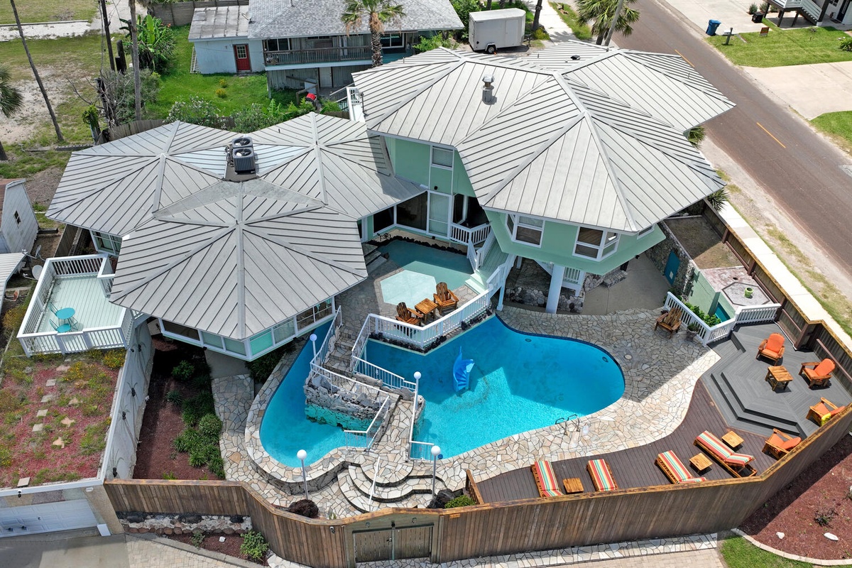 Aerial view of a distinctive vacation rental featuring a stunning swimming pool surrounded by multiple pavilions with unique circular rooflines.