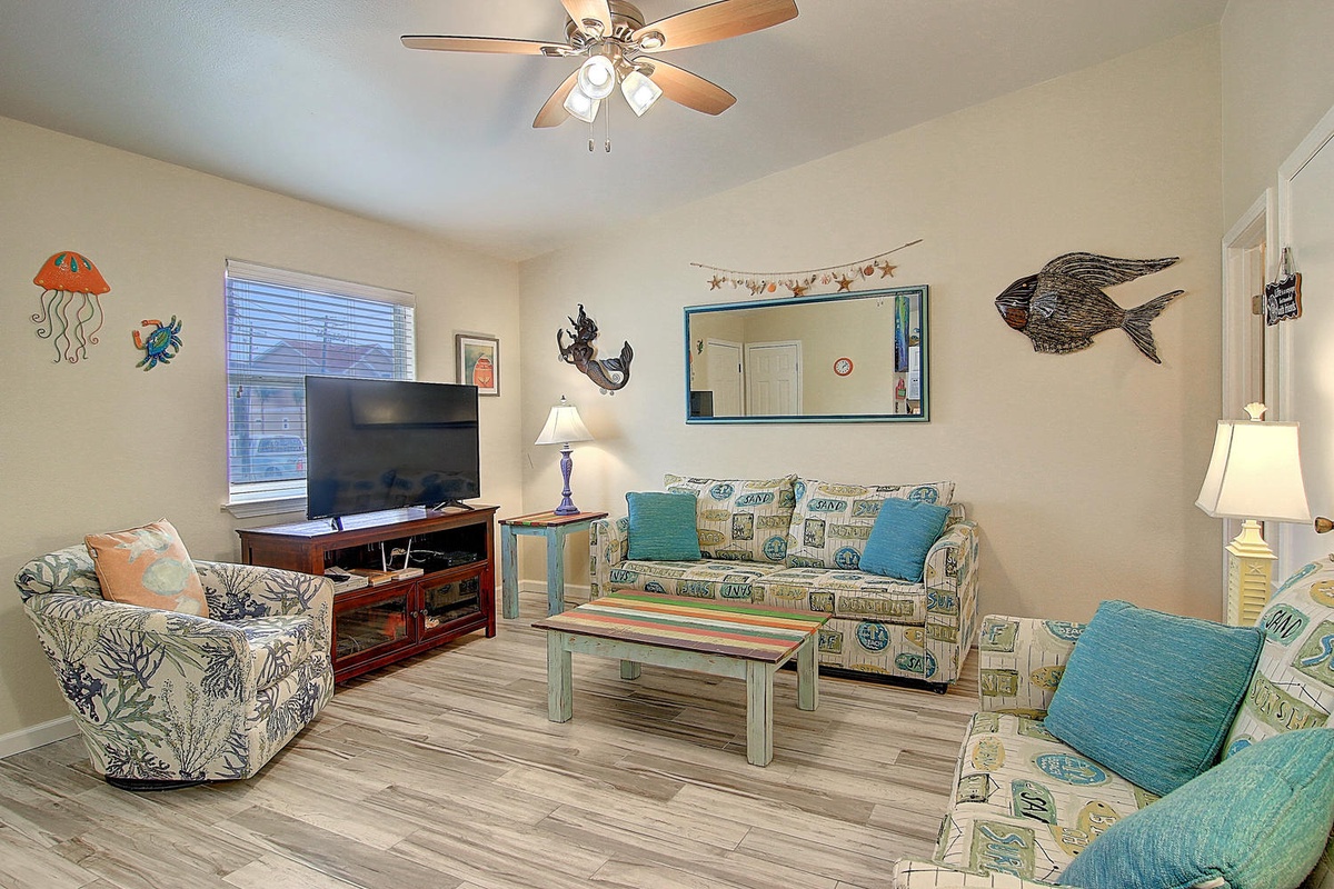 Unwind in your coastal-themed living room with comfy seating, ceiling fan, and entertainment center for cozy movie nights.