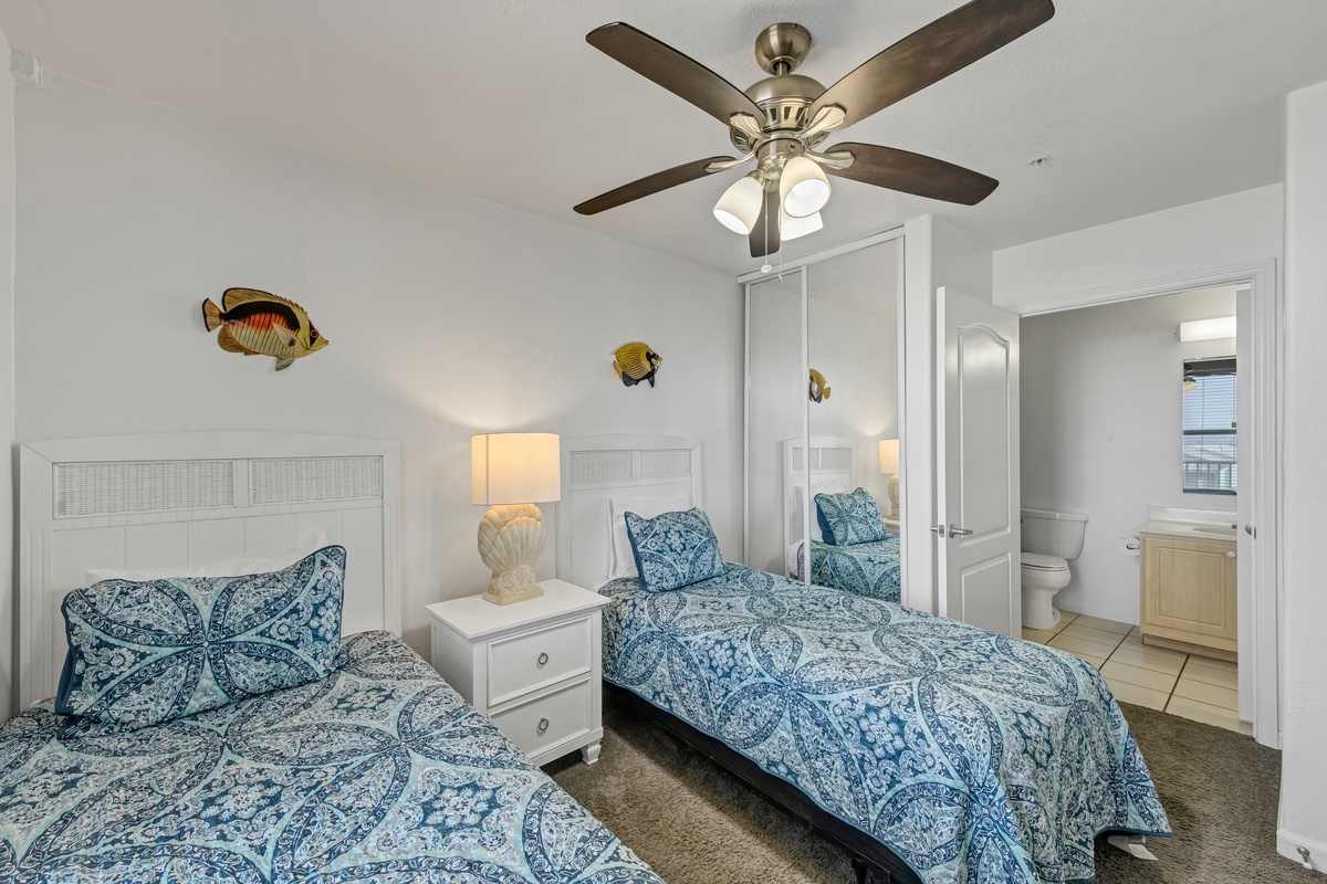 This comfortable guest bedroom offers two twin beds, coastal touches, and convenient access to a private bathroom.