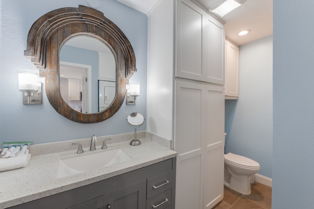 Step into your stylish bathroom featuring a stunning rustic mirror, soft blue walls, and modern vanity with quartz countertops for your daily routines.